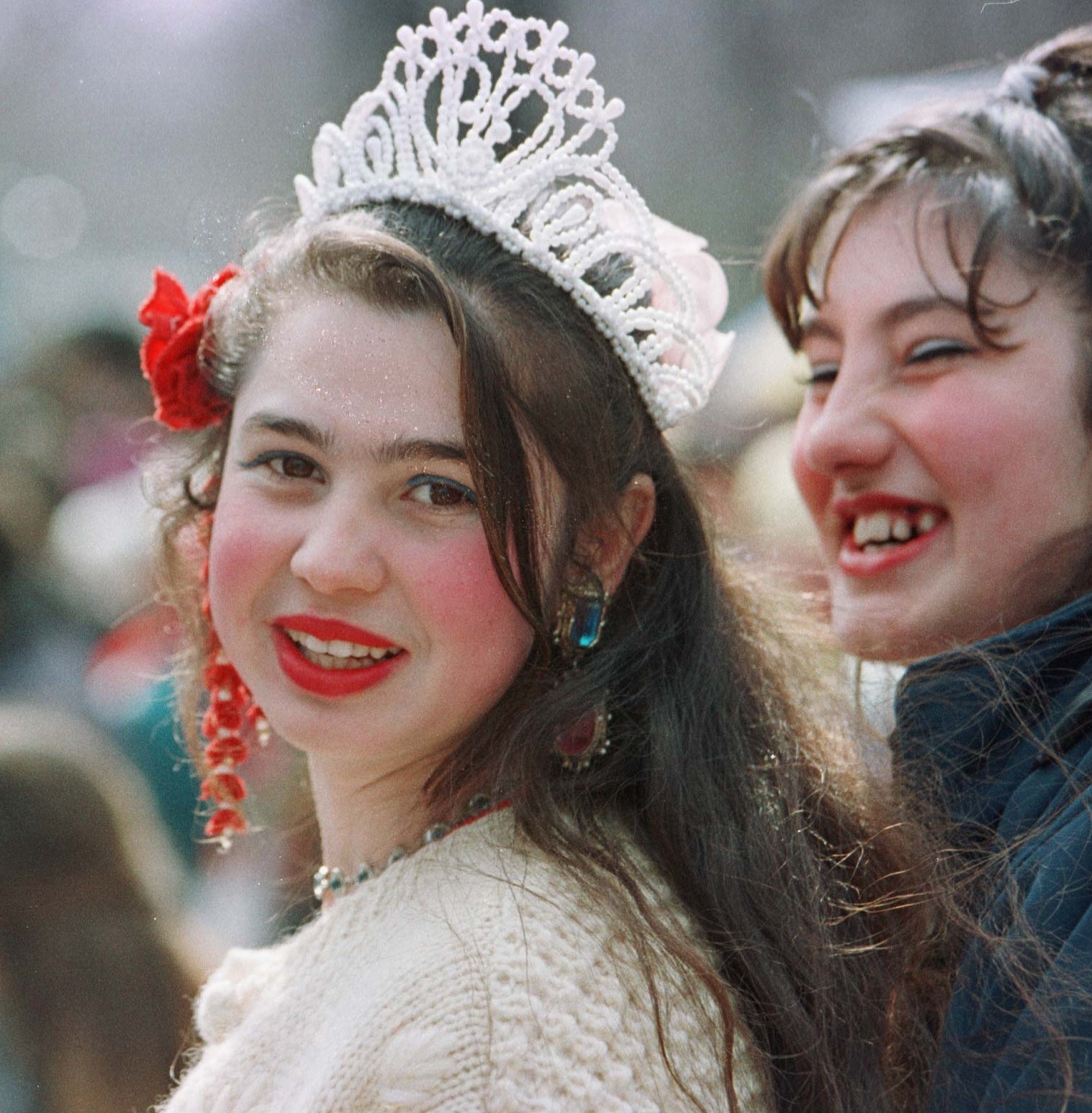 A young Romani woman smiles while wearing a tiara, awaiting selection as a bride.