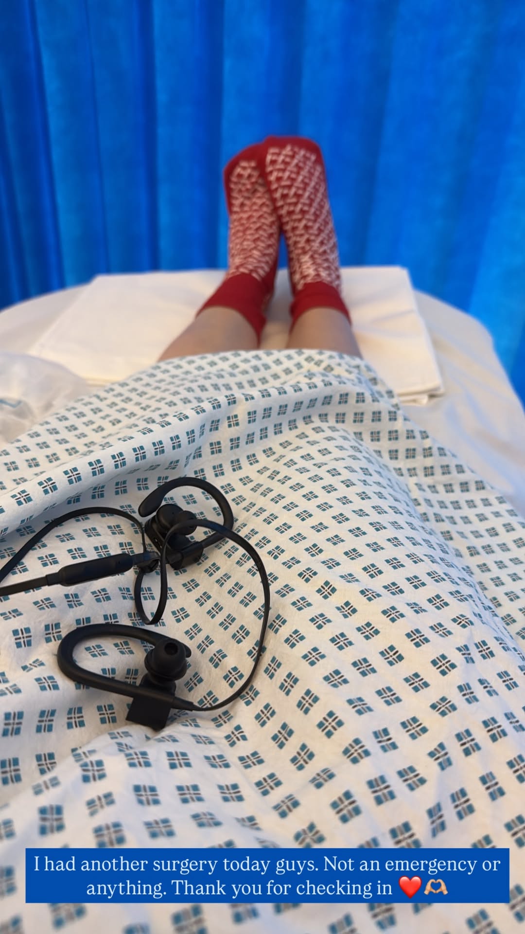 Person in hospital gown and red socks; earphones on the gown.