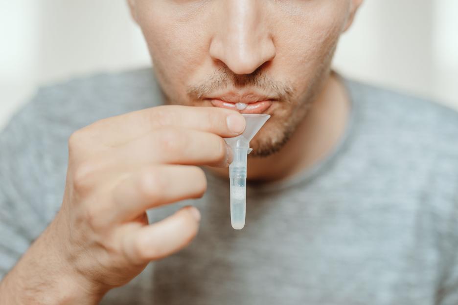 Person using a funnel to collect a saliva sample for a COVID-19 test.