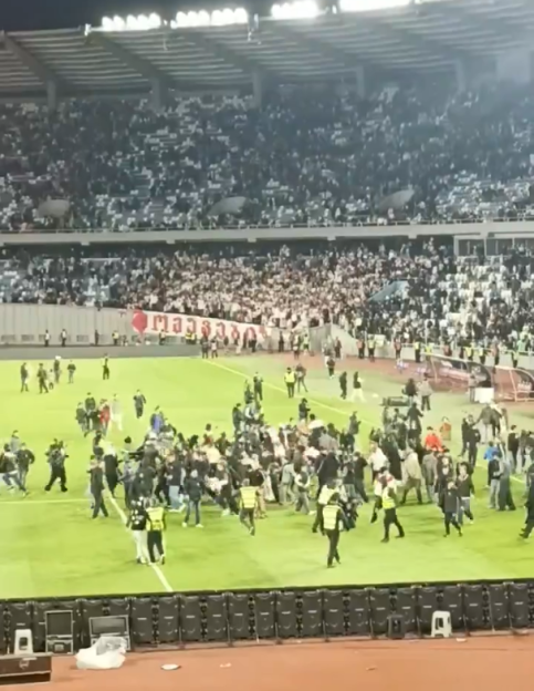 Crowd of people rushing onto a soccer field.