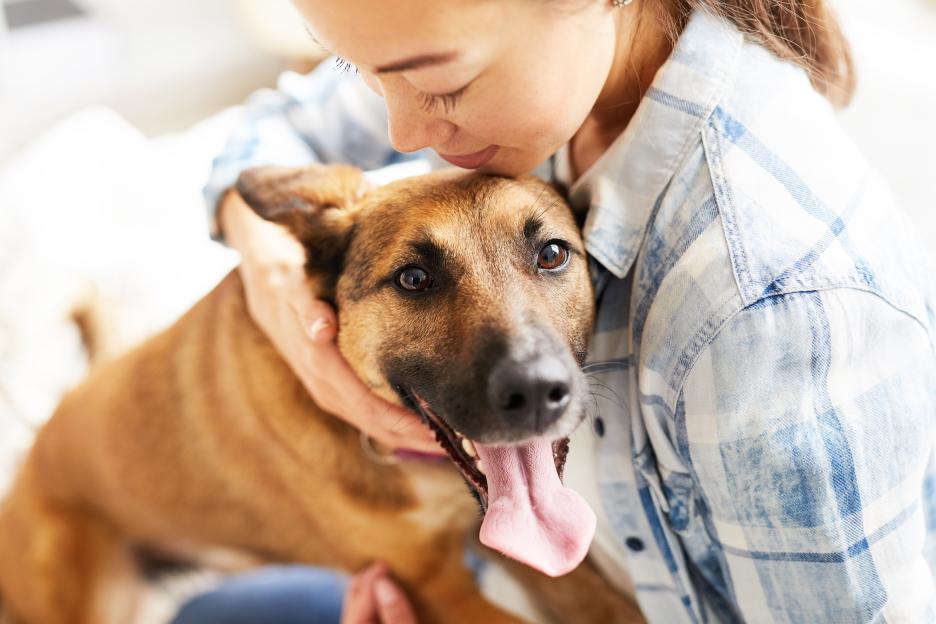 Smiling Asian woman hugging her dog.