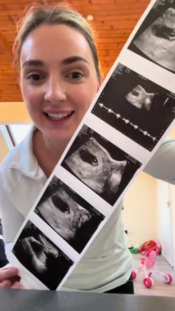 a woman holds up an ultrasound that says ' pregnancy ' on it