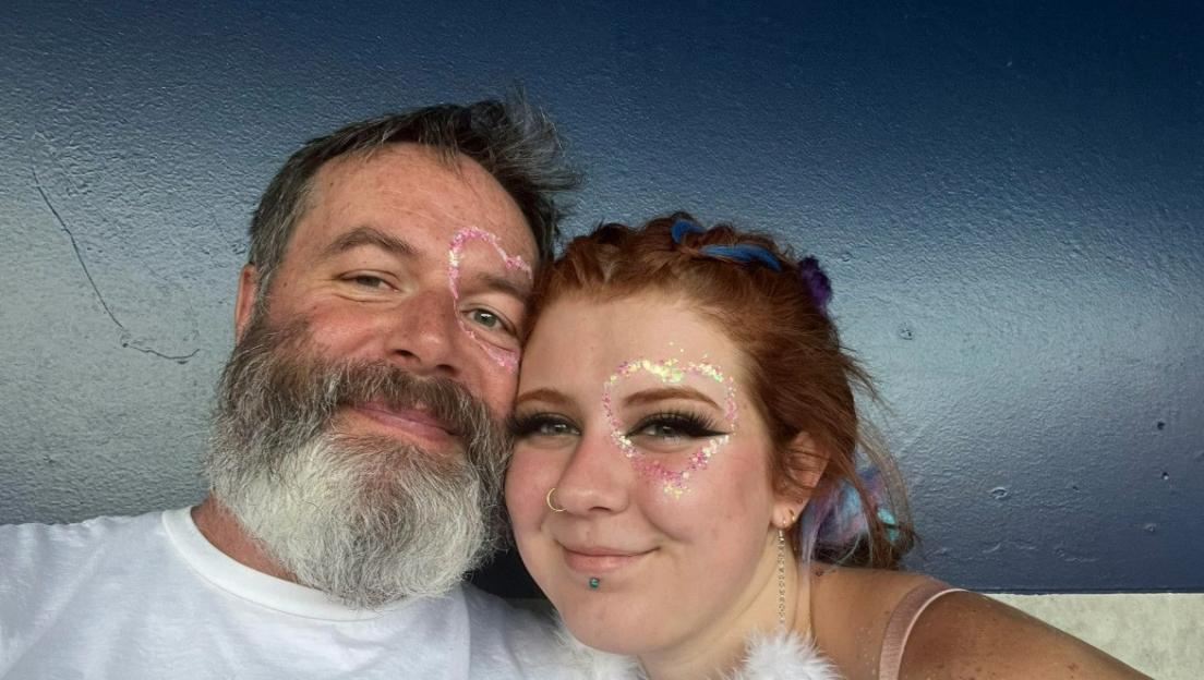 Close-up photo of a couple with glitter heart designs on their faces.