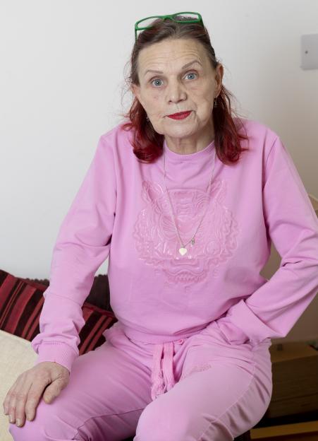 A woman in a pink tracksuit sits for a portrait.