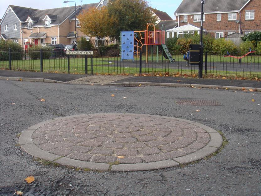 Circular paved area in a residential street near a playground.