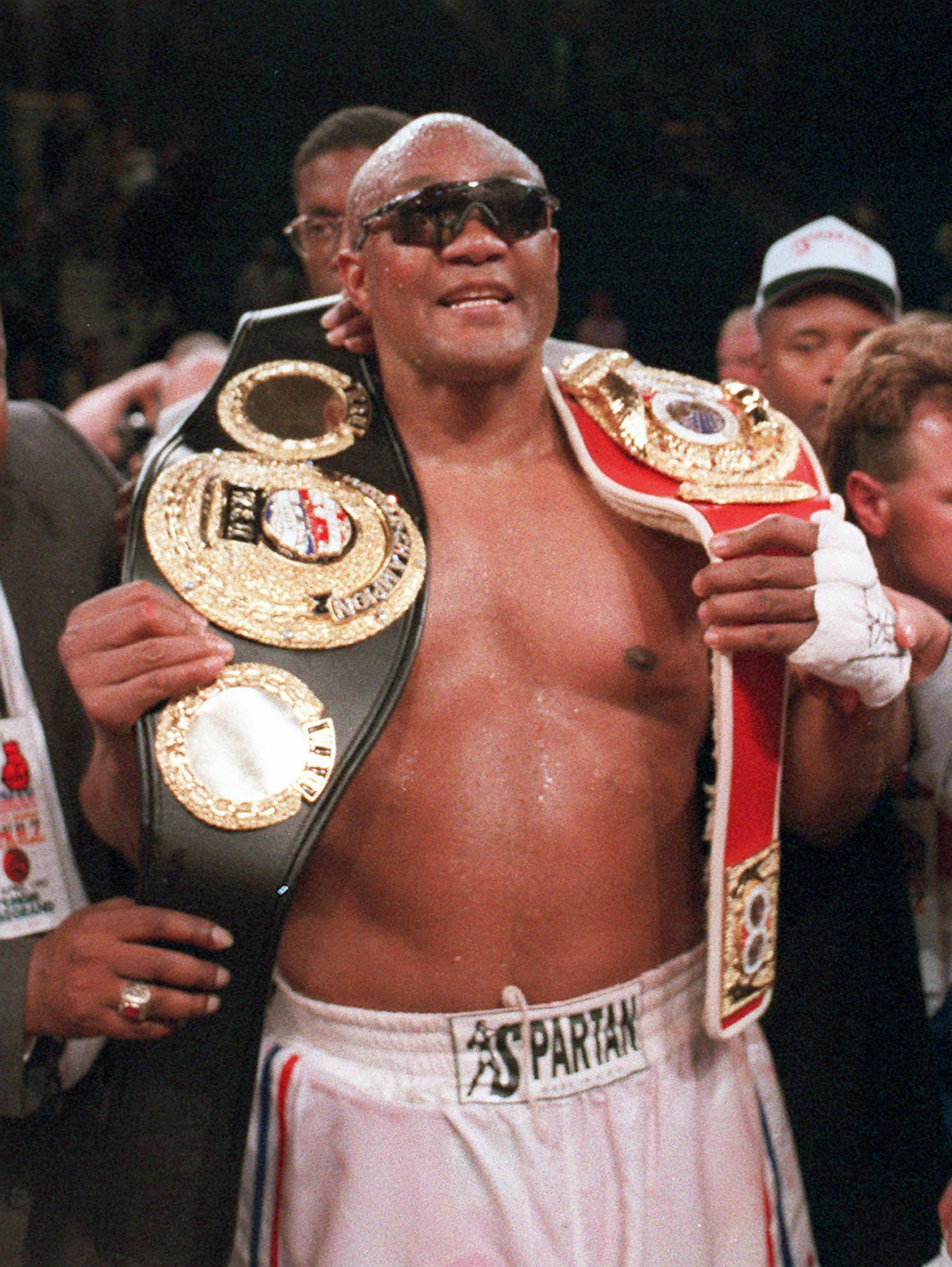 George Foreman holding up his IBF Heavyweight Championship belts.