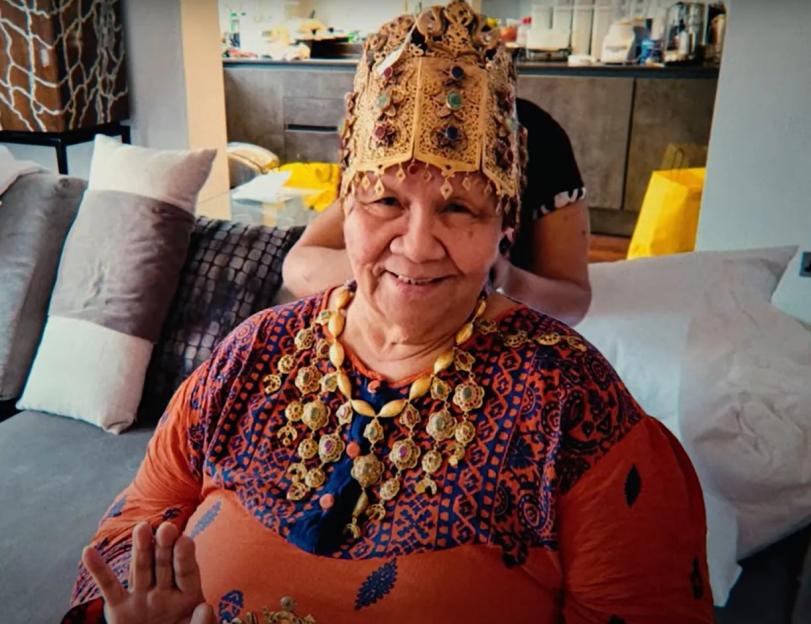 Woman wearing ornate gold headdress and necklace.