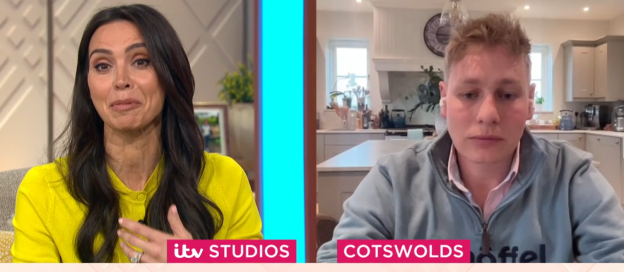 Screenshot of a split-screen showing a woman in a yellow shirt on a television program and a man in a light blue sweatshirt appearing via video link from his kitchen.