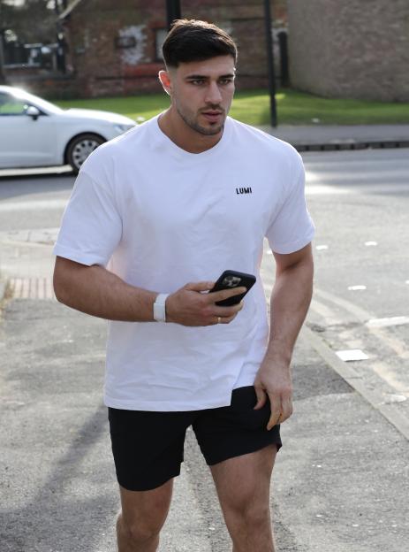 Tommy Fury walking down the street, looking at his phone.