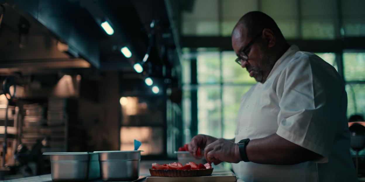 Chef arranging strawberries on a tart.