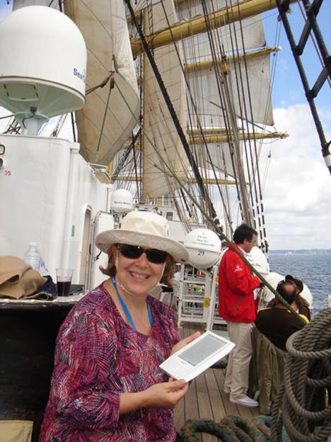 Woman on a tall ship reading an e-reader.