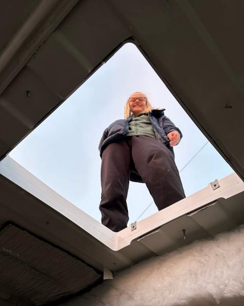 Woman standing in van roof hatch.