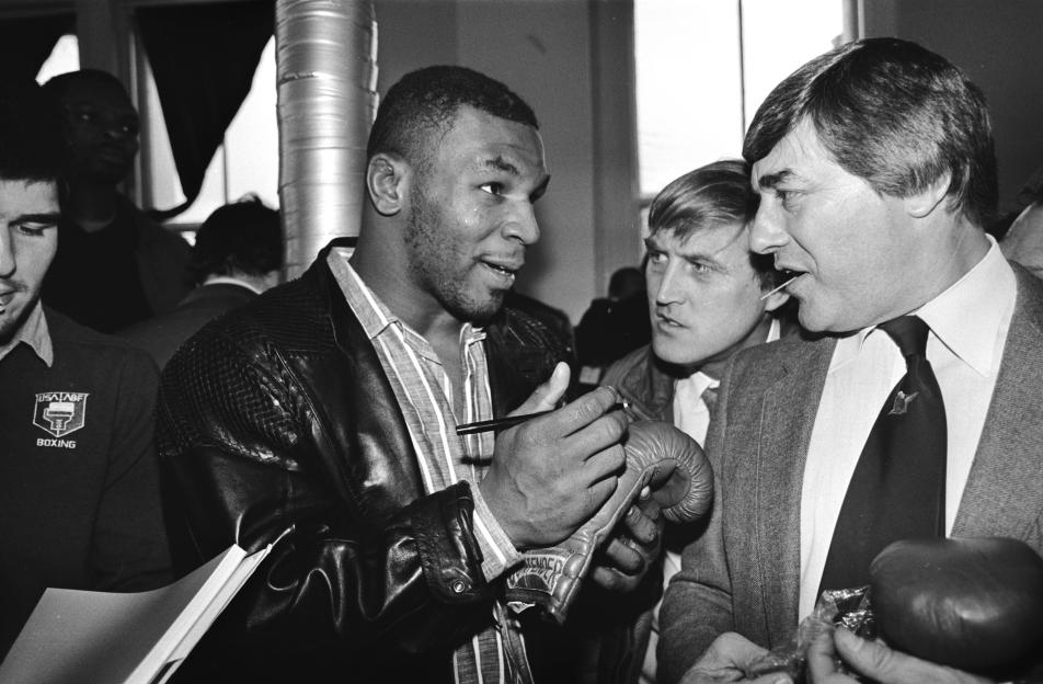 Mike Tyson signing a boxing glove for Frank Bruno in London.