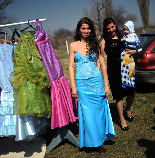 A Roma girl trying on a wedding dress at an open-air bride market.