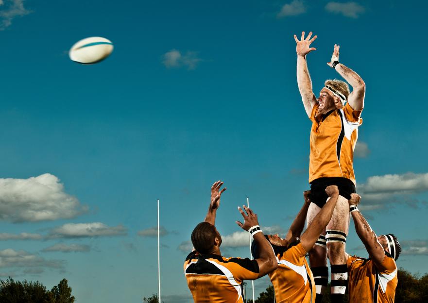 Rugby player catching a ball thrown by his teammates.