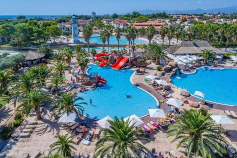 Aerial view of a resort pool area with water slides and palm trees.