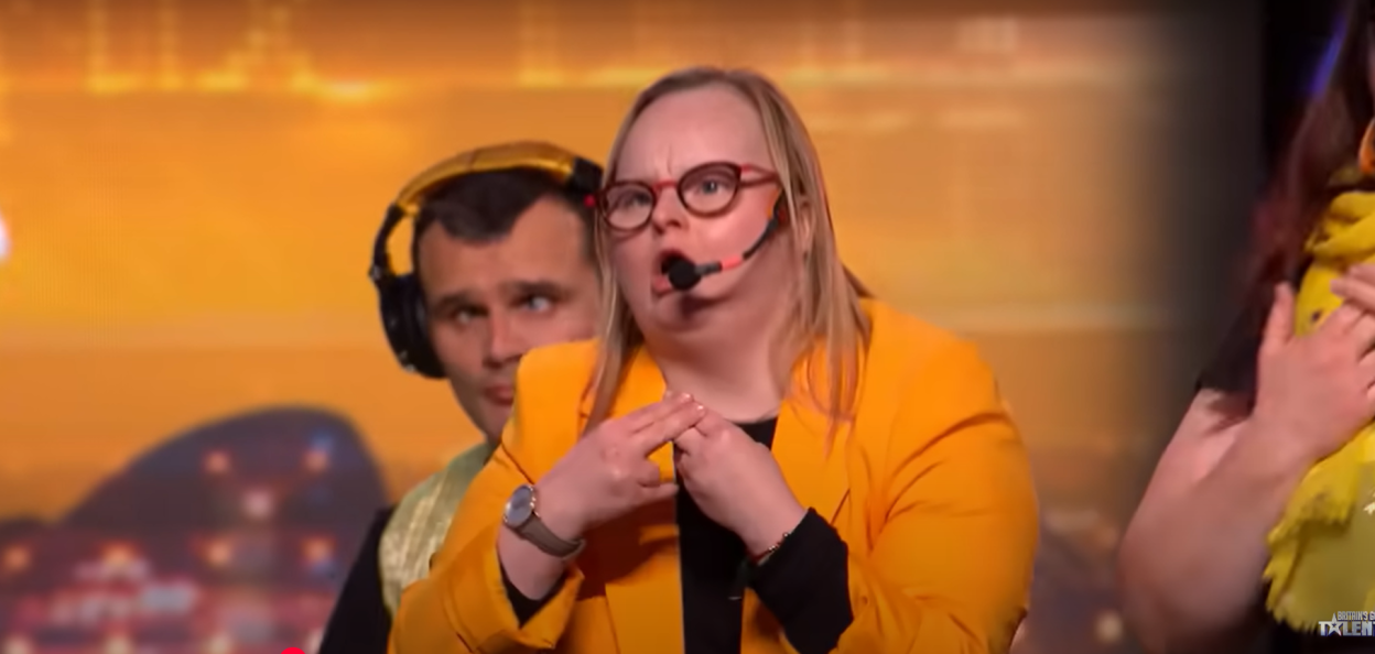 Woman in a yellow jacket speaking into a microphone.