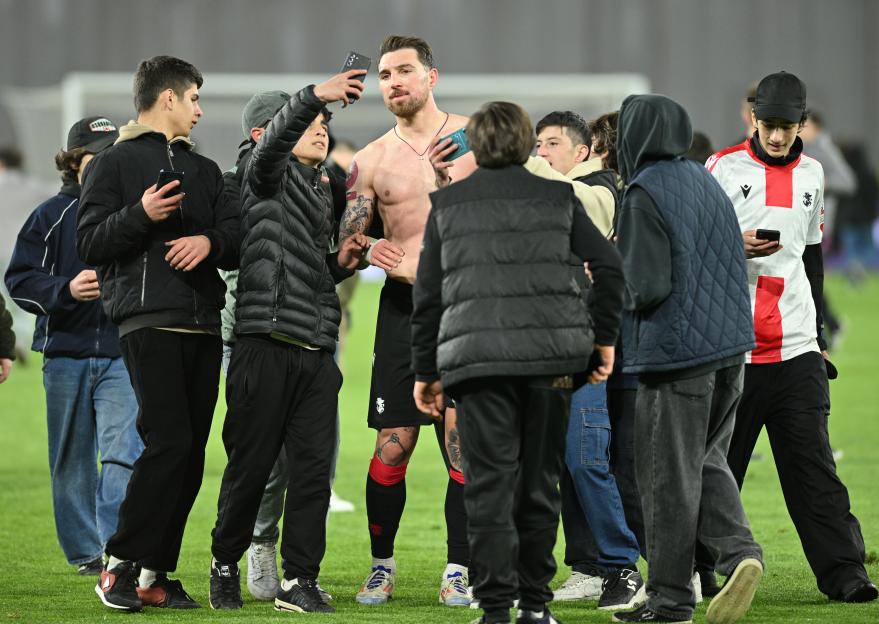 Fans taking selfies with a shirtless soccer player.