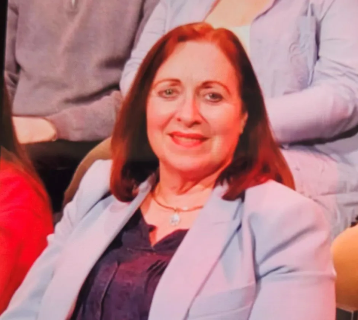 Woman in light blue blazer smiling.