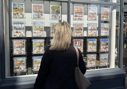 Woman looking at real estate listings in a shop window.