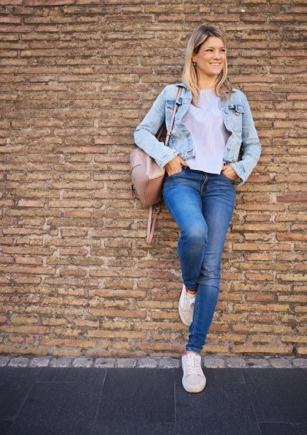 Woman leaning against a brick wall.