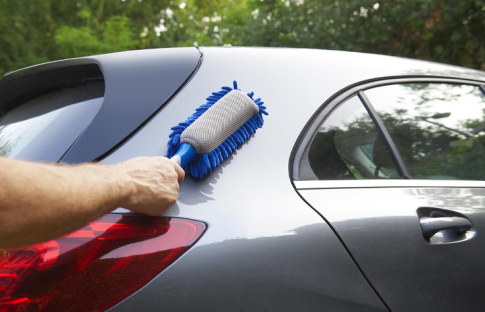 Person cleaning a car with a detailing brush.