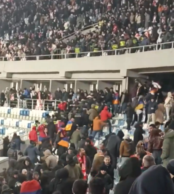 Crowd of people fighting in a stadium.