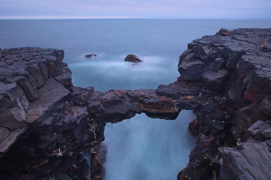 Ocean waves crashing through a natural rock arch.