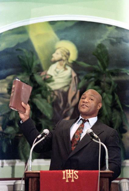 George Foreman, heavyweight boxer and preacher, holding a Bible and giving a sermon.