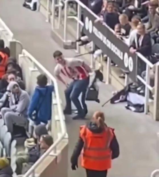 A man wiping his backside with a flag in a stadium.