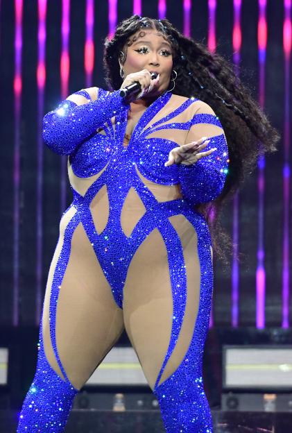 Lizzo performing on stage in a blue sequined bodysuit.