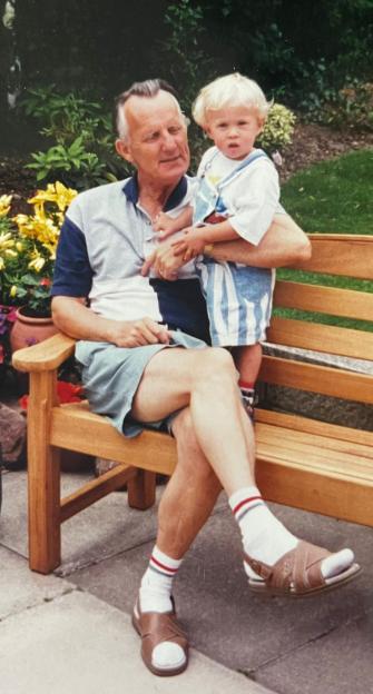 Older man sitting on a bench holding a toddler.