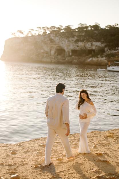 Pregnant woman and man on a beach.