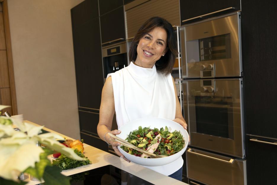 Woman holding a healthy salad in her kitchen.