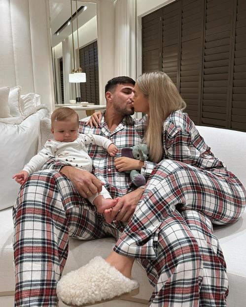 Couple kissing in matching pajamas with their baby.