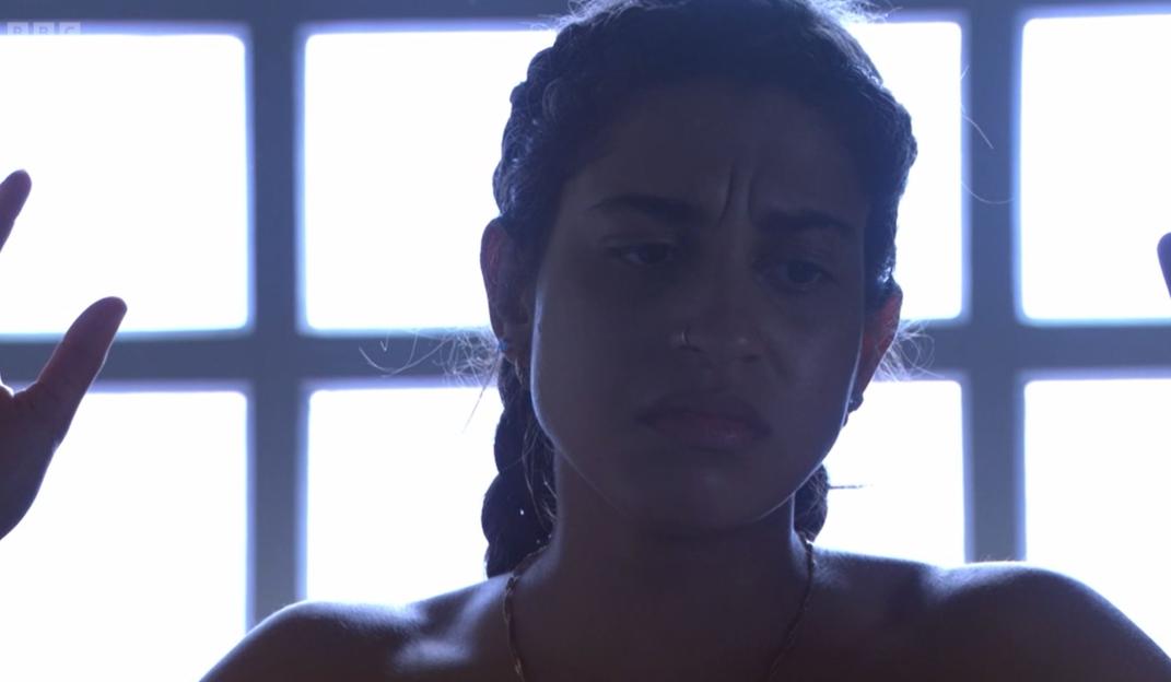 Close-up of a young woman looking distressed, her hands raised.