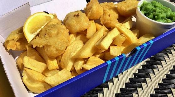 Fish and chips with mushy peas and lemon.