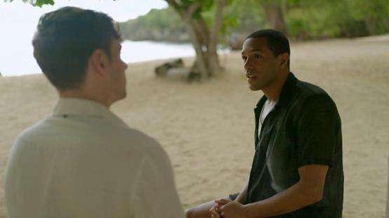 Michael Gunning and Tom Daley on a beach, in conversation.