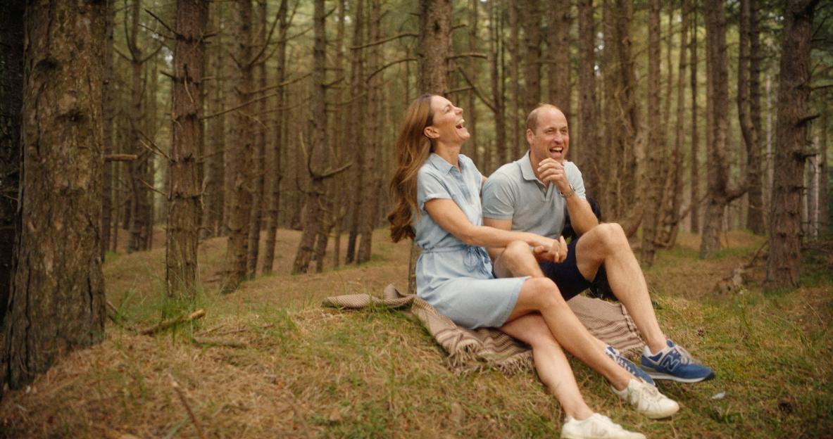 Prince William and Princess Catherine laughing together in a forest.