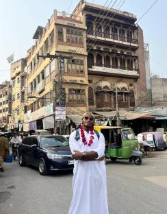 Man in white thobe standing on a street in Pakistan.