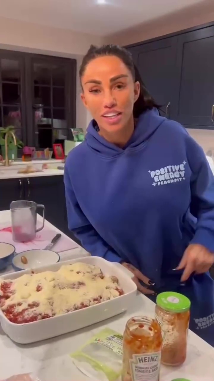 Katie Price in her kitchen preparing a dish topped with cheese.