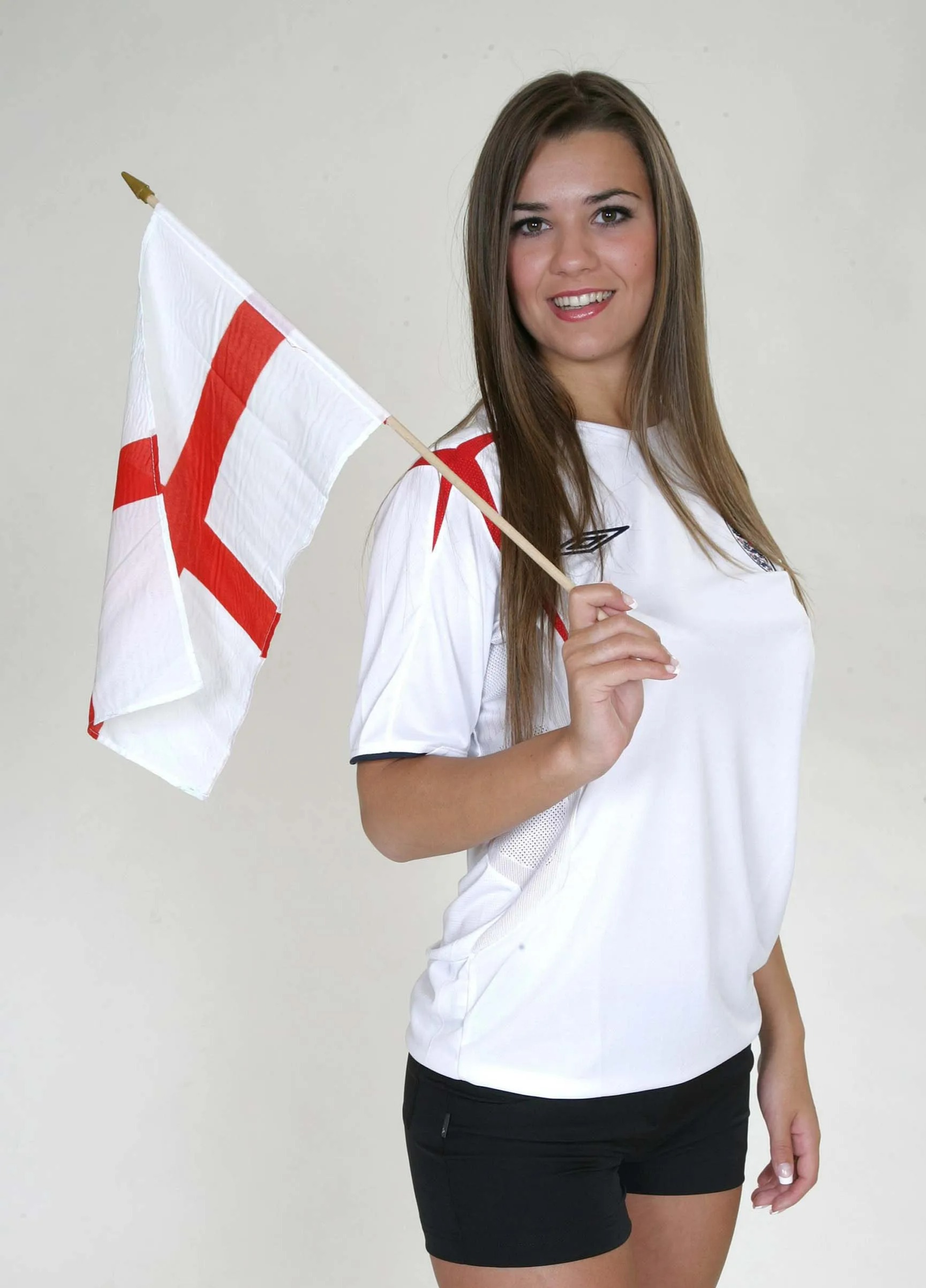 Woman in England football shirt holding small English flag.