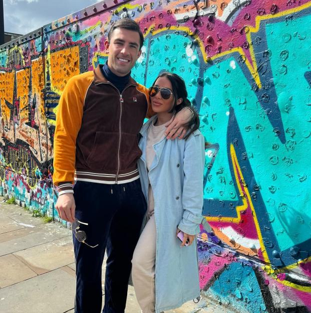 Couple posing in front of graffiti wall.