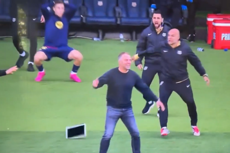 Soccer coaches reacting to a laptop on the field.