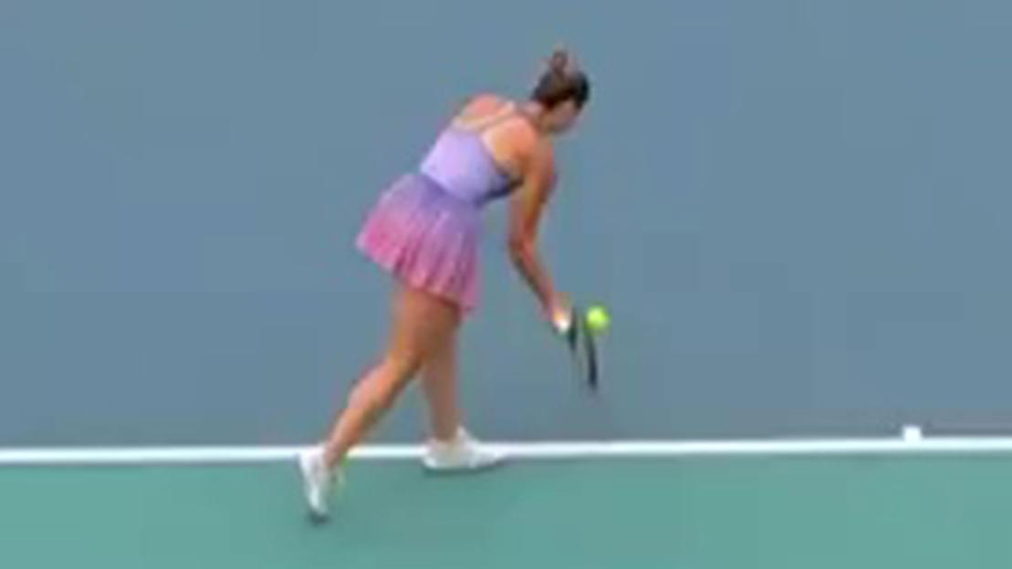 Tennis player bending down to pick up a tennis ball.