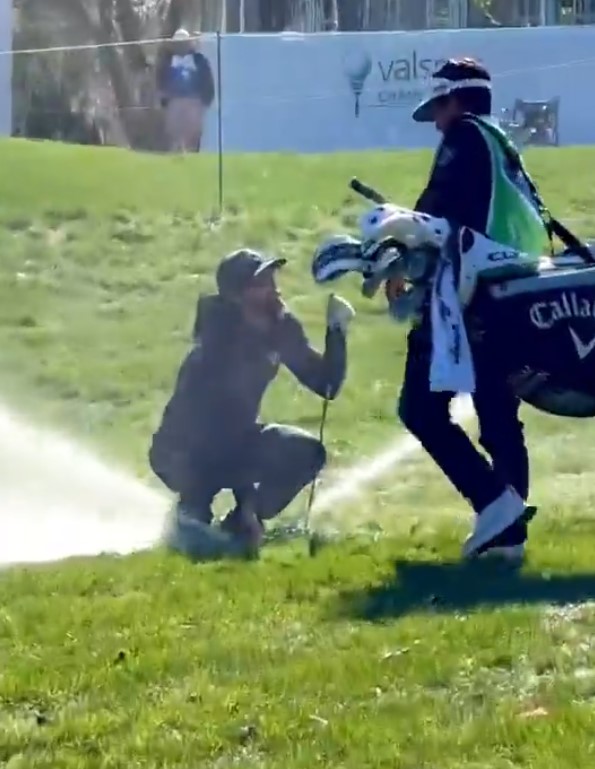 Golfer Adam Hadwin accidentally activates a sprinkler while retrieving his club.