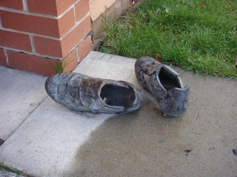 A pair of worn-out shoes on a sidewalk.