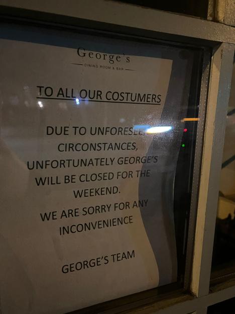 Photo of a sign on George's Dining Room and Bar door announcing its closure for the weekend due to unforeseen circumstances.