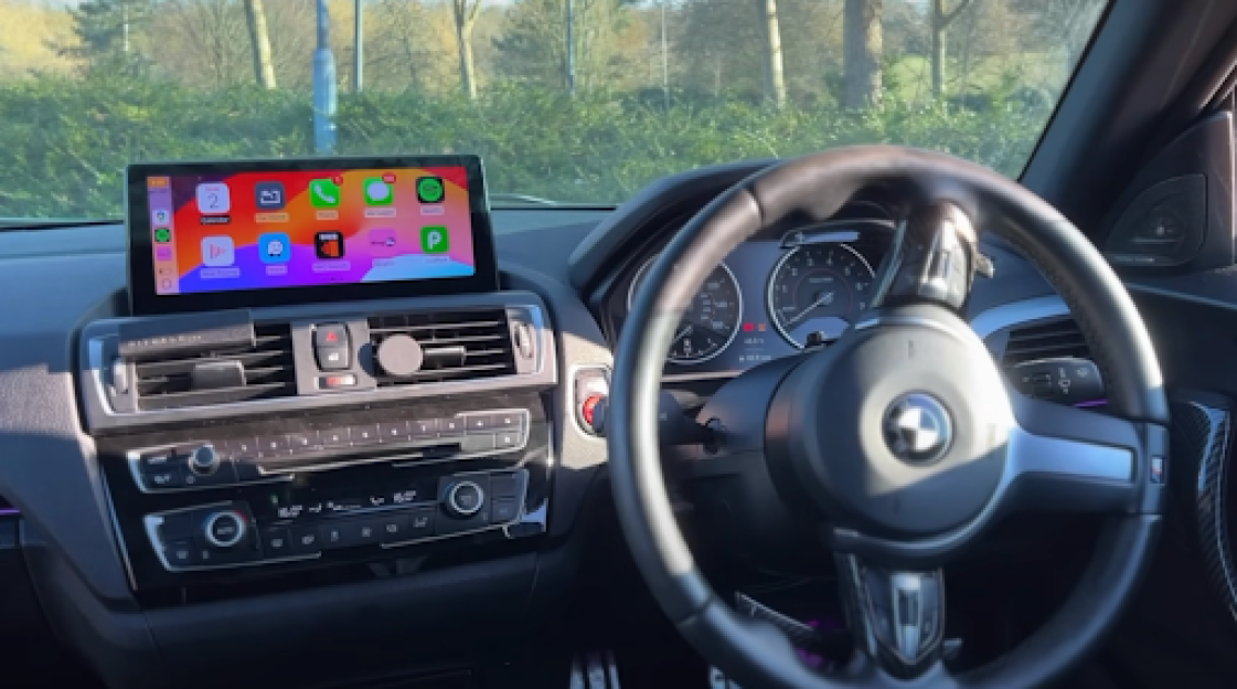 BMW interior with an aftermarket infotainment screen displaying iOS apps.