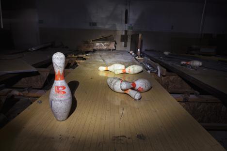 Abandoned bowling alley with several bowling pins on the lane.